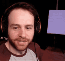 a man with a beard wearing headphones is smiling and looking at the camera