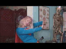 a woman in a super hero costume is standing in front of a skeleton and a poster that says the brain