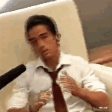 a man in a white shirt and tie is sitting on a couch