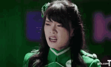 a woman in a green uniform is smiling in front of a sign that says ?