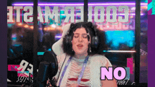 a woman wearing headphones is sitting in front of a microphone and says no