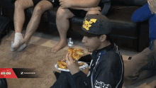 a man eating a slice of pizza with a twitch logo on his sleeve