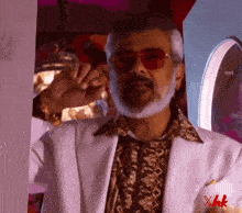 a man with a beard wearing sunglasses and a white jacket with the letters xhk on the bottom