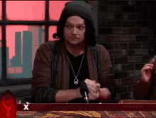 a man is sitting at a table with a red x in the corner
