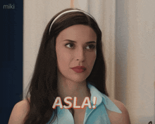 a woman in a blue shirt says " asla " in orange letters