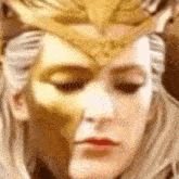 a close up of a woman wearing a gold mask and a crown .