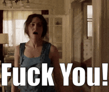 a woman in a blue tank top is standing in front of a sign that says fuck you