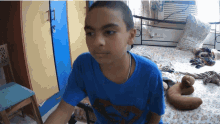 a boy in a blue shirt is sitting on a bed in a room