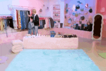 a woman is standing in front of a table full of clothes and shoes