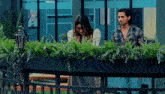 a man and a woman standing next to each other in front of a planter