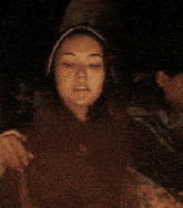 a woman in a hooded sweatshirt is sitting in a dark room holding a bag of popcorn .