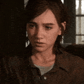a woman with freckles on her face is wearing a brown shirt and looking at the camera .