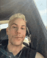 a young man with blonde hair is sitting in a car