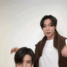 two men are standing next to each other with their arms in the air and making funny faces .