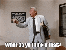 a man in a suit and tie is standing in front of a sign that says prisoner grievance procedure