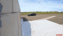 a bmw is parked on the side of the road in front of a concrete wall with thinkjules written on the bottom