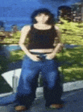 a woman wearing a black tank top and blue jeans