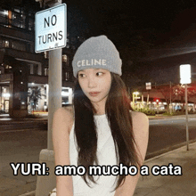 a woman wearing a celine beanie stands under a no turns sign