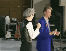 a man in a blue suit is smoking a cigarette while standing next to a woman