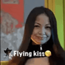 a woman with long hair is smiling with the words `` flying kiss '' above her .
