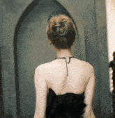the back of a woman wearing a black dress and a tiara