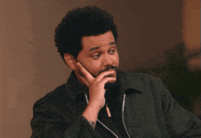 a man with a beard has his hand to his chin