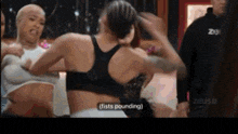 a woman in a black sports bra says " fists pounding " while standing next to another woman