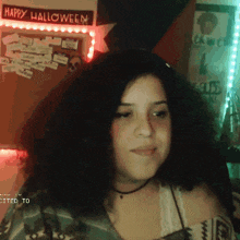 a woman is smiling in front of a happy halloween sign
