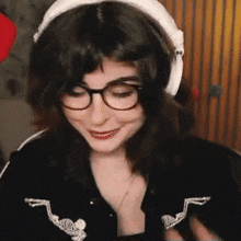 a woman wearing glasses and headphones is smiling while looking down .