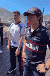 a man wearing a red bull shirt stands next to another man wearing a white shirt