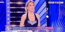 a woman in a black dress is on a television screen with trash italiano written on the bottom