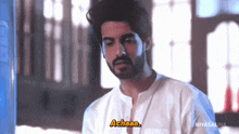 a man with a beard is wearing a white shirt and says achaaa