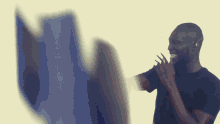 a man in a black shirt is smiling while holding his hand to his mouth