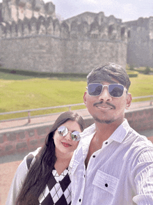 a man and a woman are posing for a picture in front of a stone wall