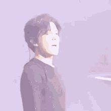 a man in a black shirt is standing on a stage with his mouth open and a purple background .