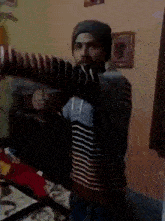 a man wearing a beanie and a striped shirt is standing in a room .