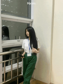 a woman standing in front of a window with hypic written on the bottom right
