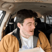 a man wearing glasses and a yellow jacket is sitting in the back seat of a car