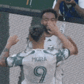 a soccer player wearing a number 9 jersey hugs another player