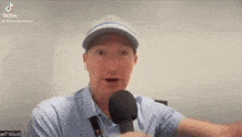 a man wearing a hat and tie is holding a microphone and talking into it .