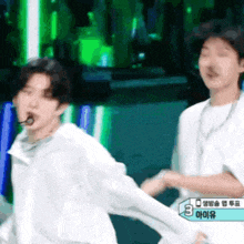 a man in a white shirt is holding another man 's hand while dancing on a stage .