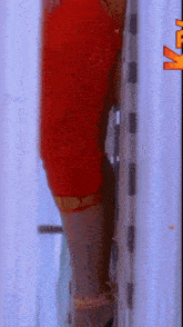 a woman in a red dress is leaning against a wall with a tv logo in the corner