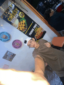 a man taking a selfie in front of a sign that says french fries on it