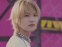 a close up of a person wearing a necklace and a white shirt