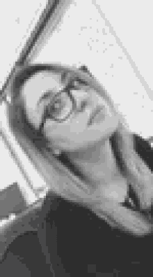 a black and white photo of a woman wearing glasses and a black shirt .
