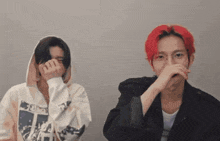a man with red hair is covering his mouth with his hand