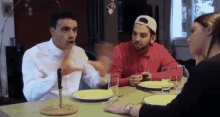 a group of people are sitting at a table with plates and glasses and a knife in the middle of the table