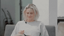 a woman in a white sweater is smiling while holding a pair of scissors in her hand