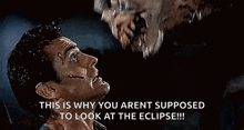 a man is looking at a monster with its mouth open in a horror movie .