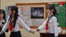 two girls in school uniforms holding hands in front of a bulletin board that says free fire